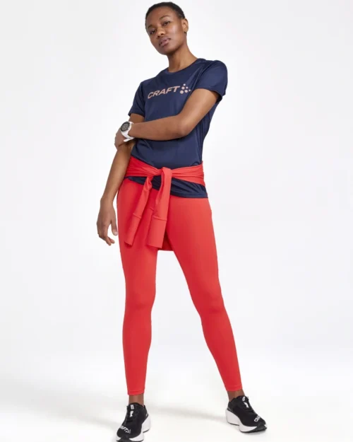 Nainen poseeraa oransseissa treenitrikoissa