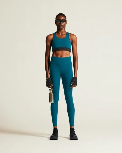 Nainen poseraa petrolinsinisissä treenitrikoissa