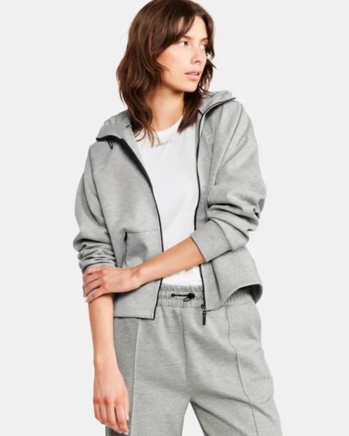 Nainen poseeraa harmaa vetoketjullinen huppari yllään